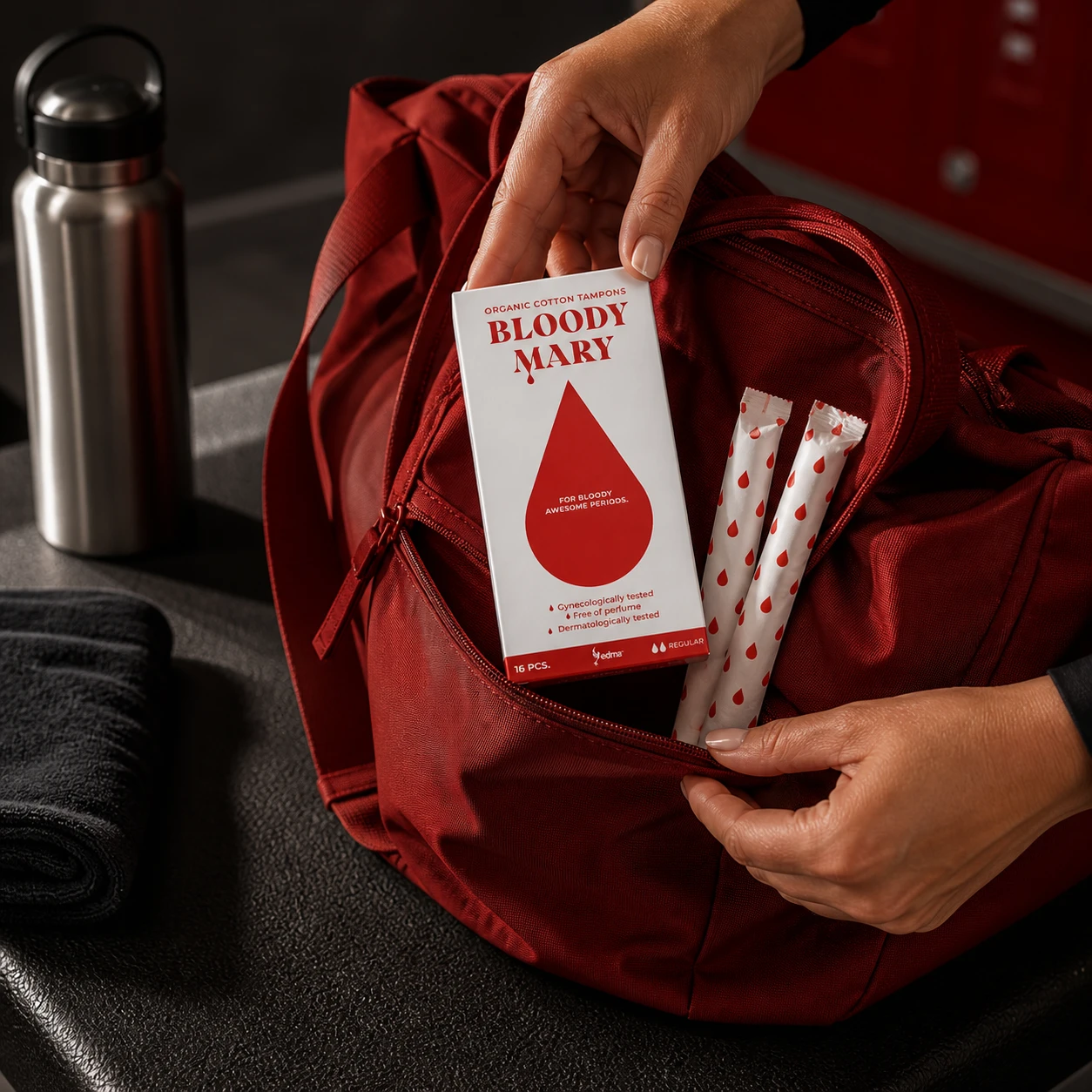 Hands placing a Bloody Mary Regular box and wrapped tampons into a red gym bag