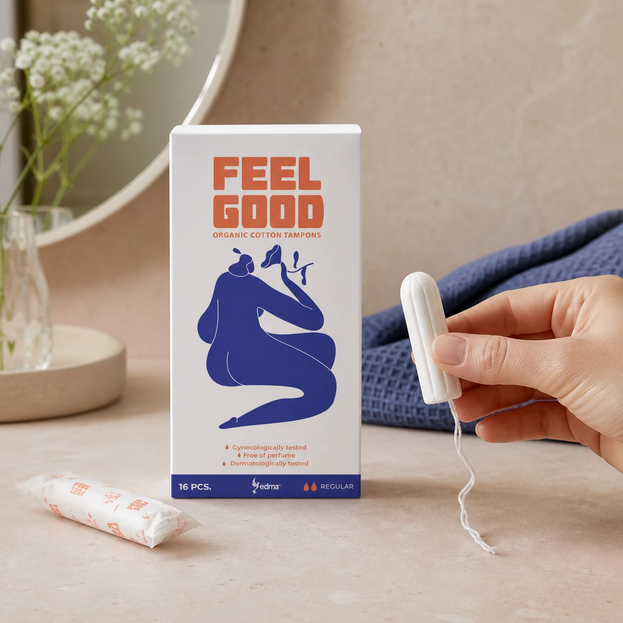 Hand holding an applicator-free organic cotton tampon beside a Feel Good Regular box