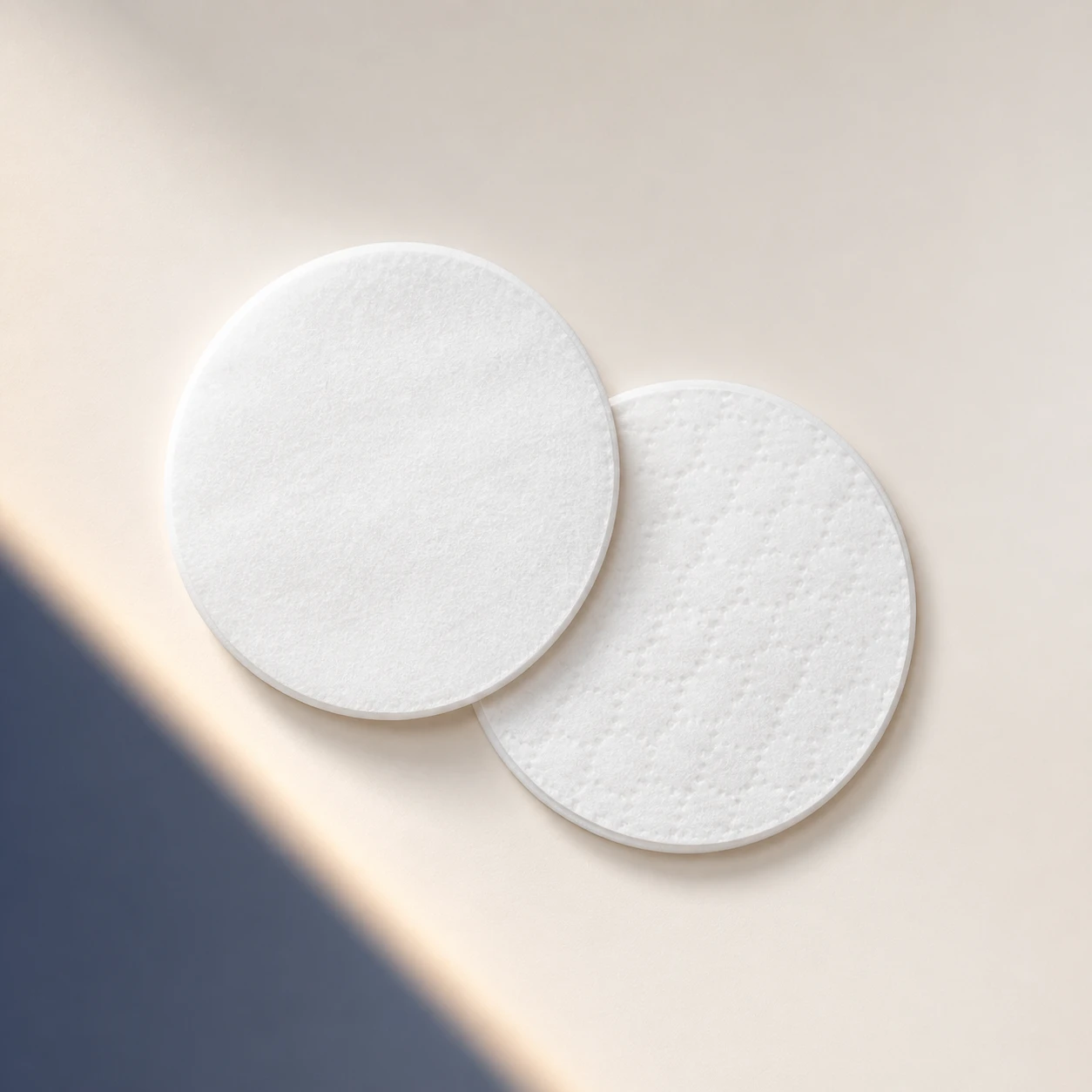 Top-down comparison of the smooth and lightly textured faces of NightWatch cotton pads