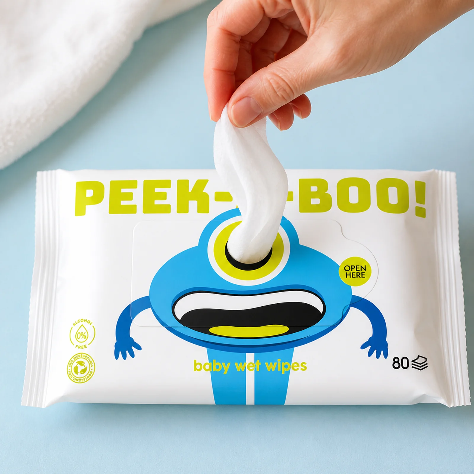 Hand pulling one white wet wipe from a Peek-a-Boo pouch